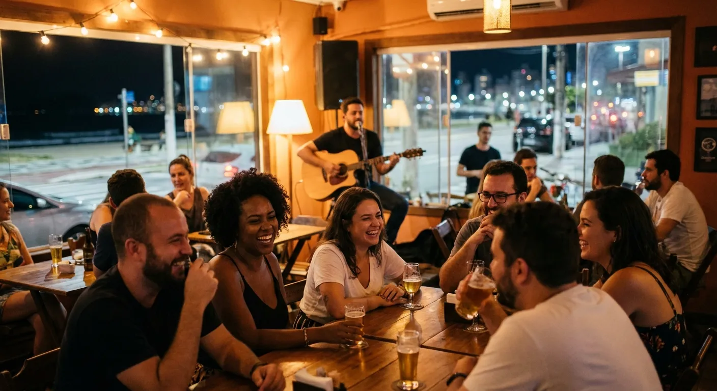 Grupo de amigos sorrindo e se divertindo em um bar, enquanto músico toca violão ao fundo.
