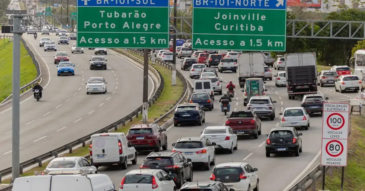 Trânsito intenso na BR-101 com placas indicativas e radares de velocidade visíveis na via.