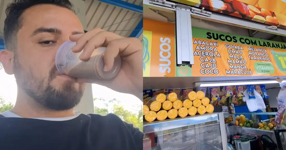 Homem bebendo suco em um quiosque, com frutas expostas e cardápio ao fundo.