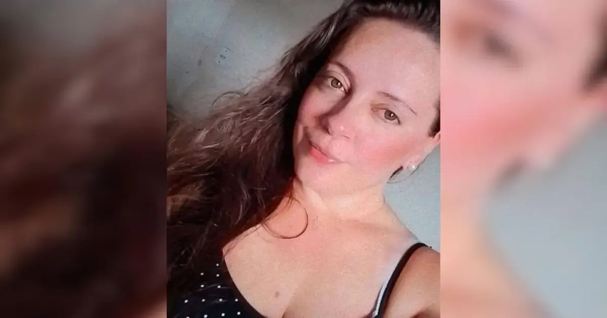 Mulher com cabelo longo e ondulado, usando blusa preta com bolinhas brancas, sorrindo para a câmera.