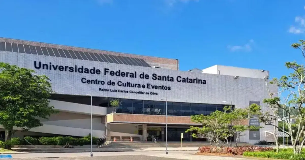 Prédio da Universidade Federal de Santa Catarina com céu azul e vegetação ao redor.