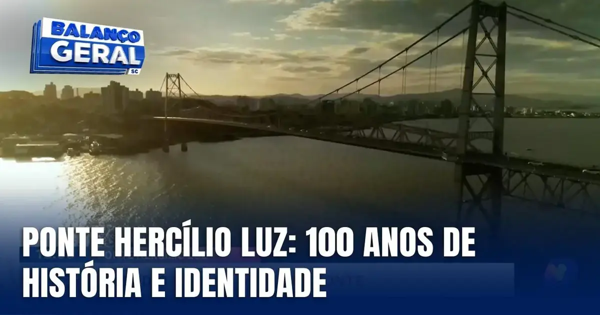 Ponte Hercílio Luz ao fundo com céu azul e nuvens, celebrando 100 anos de história em Santa Catarina.