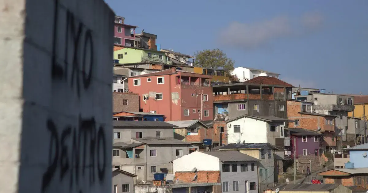 Vista de casas coloridas em área urbana de Florianópolis, com construções irregulares e céu azul.