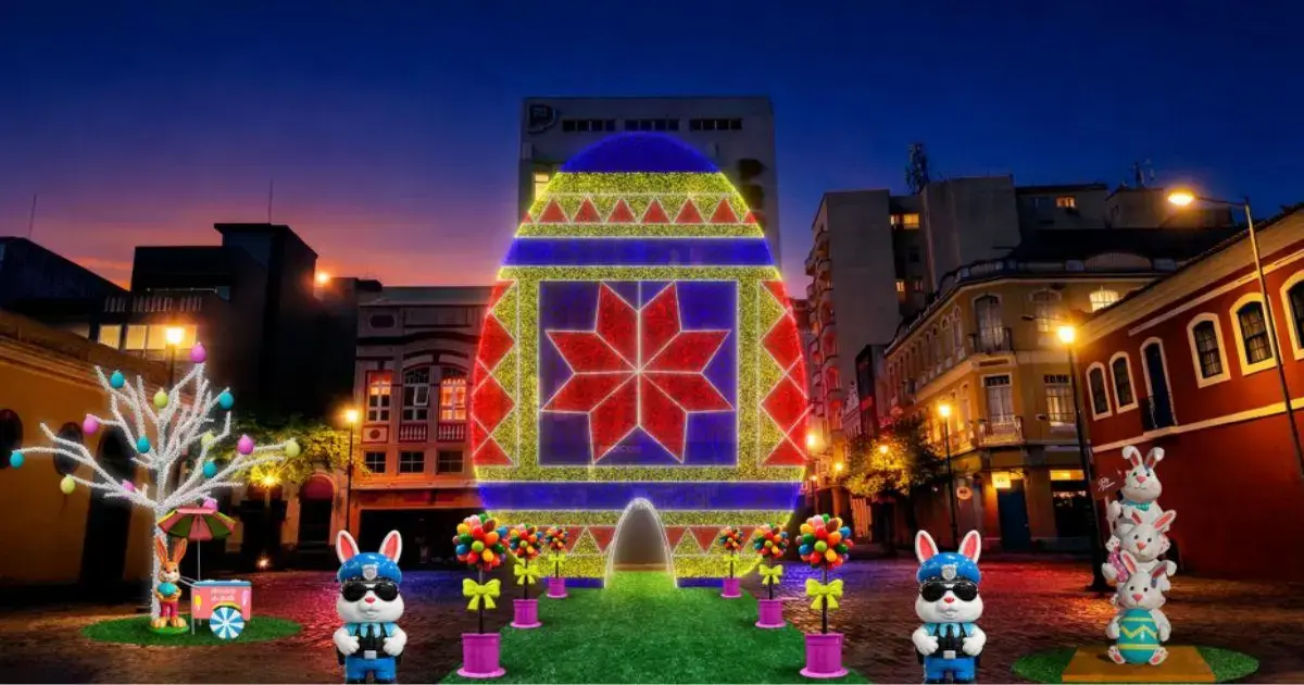 Decoração de Páscoa em Florianópolis com ovos coloridos, coelhos e árvores iluminadas em ambiente urbano.