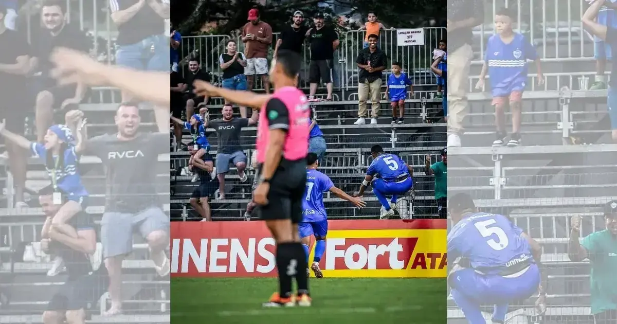 Torcedores comemoram gol em estádio, árbitro aponta para o campo, jogadores celebram ao fundo.