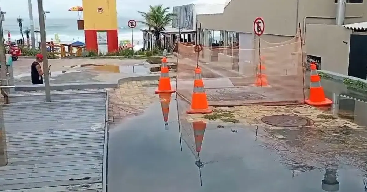 Esgoto acumulado em área da Praia da Joaquina, com cones laranjas e pessoas ao fundo, durante o Carnaval.