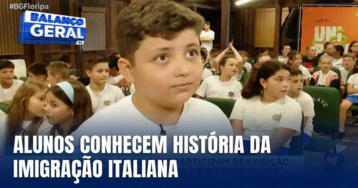 Estudantes em sala de aula assistem documentário, um aluno em destaque fala sobre imigração italiana.