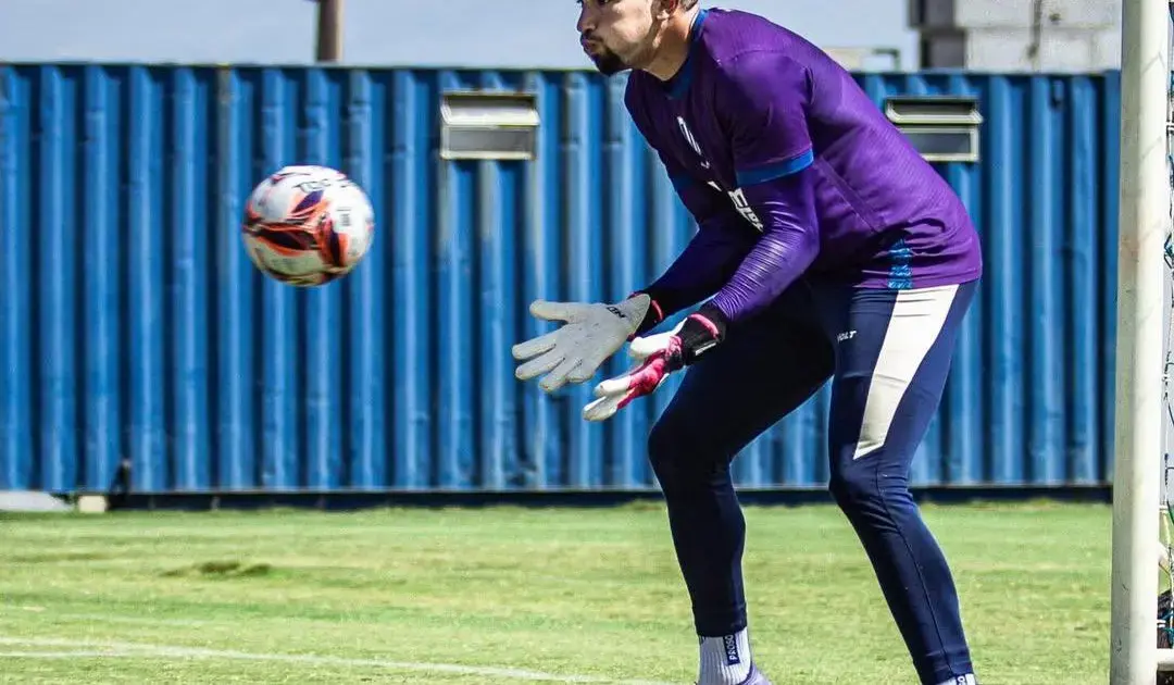 Goleiro Léo Aragão em treinamento, se preparando para defender uma bola, vestindo uniforme roxo e luvas.