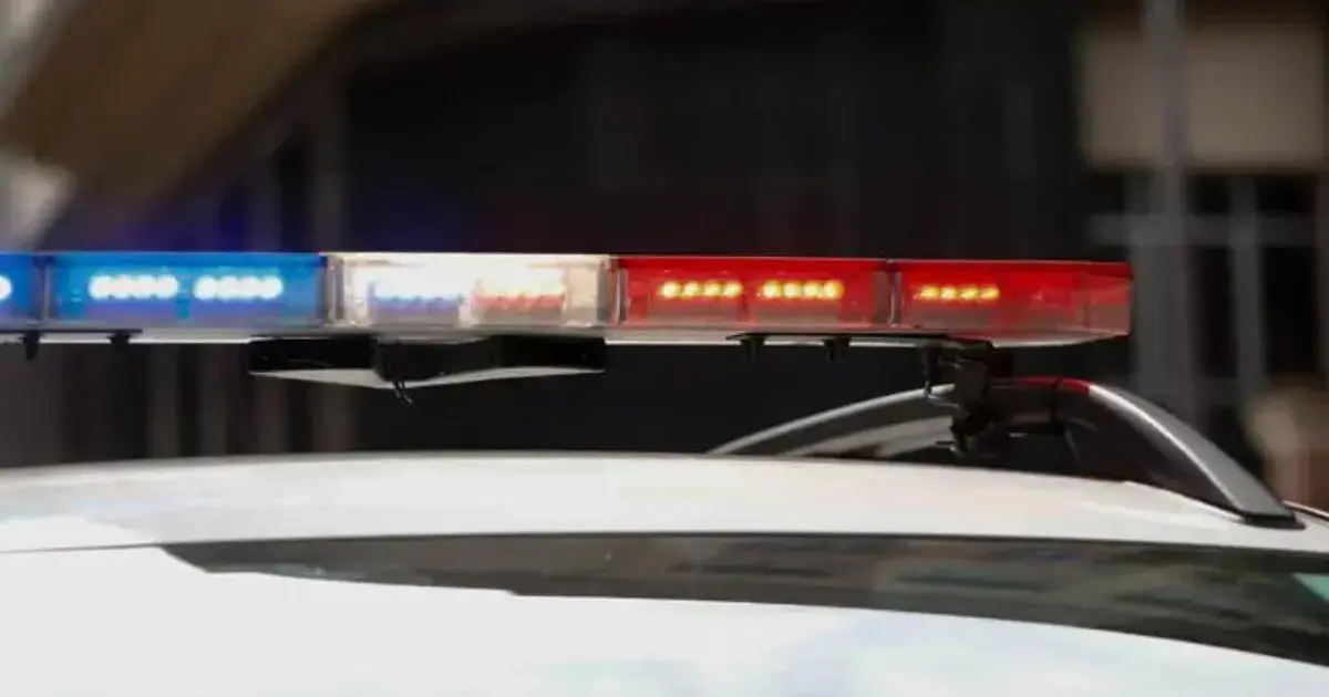 Luzes vermelha e azul em um carro de polícia estacionado em área urbana.