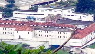 Vista aérea de um complexo prisional com telhados vermelhos e áreas verdes ao redor.