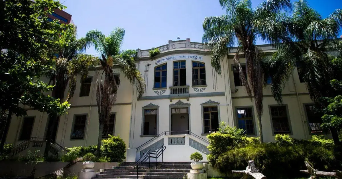 Prédio da primeira escola municipal do Centro, com palmeiras ao redor e céu azul ao fundo.
