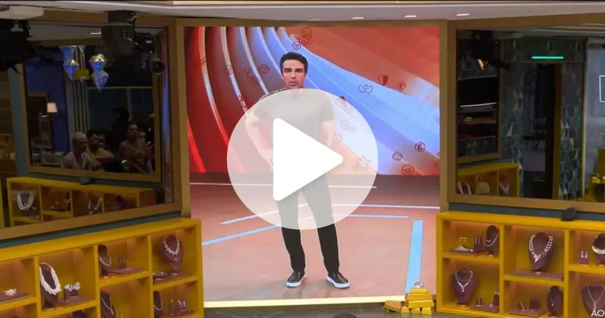 Homem em pé em um cenário de estúdio com decoração moderna e prateleiras com joias expostas.