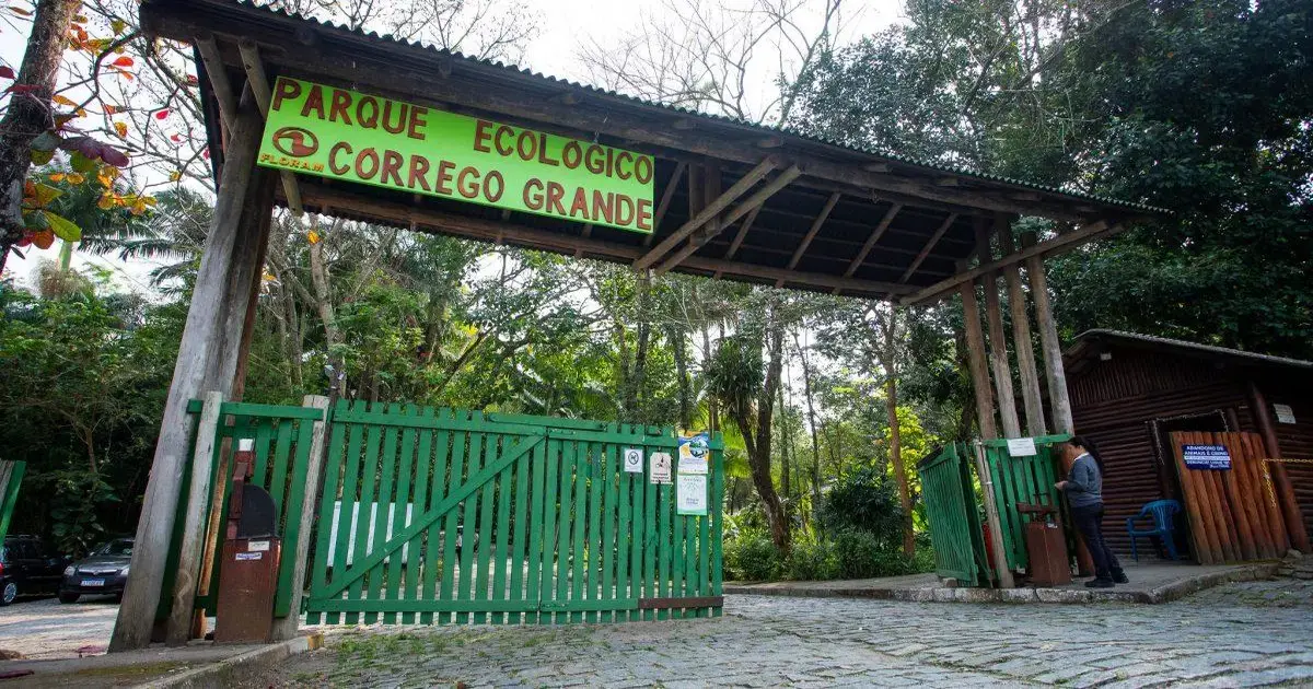 Entrada do Parque Ecológico do Córrego Grande, com portão verde e árvores ao fundo.