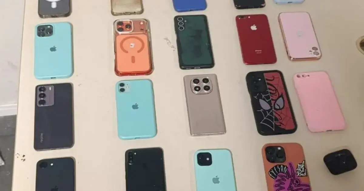 Diversos celulares de diferentes marcas e cores dispostos sobre uma mesa.