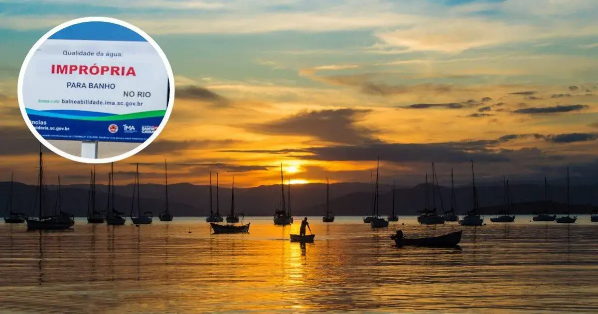 Pôr do sol na Praia de Santo Antônio de Lisboa com barcos ao fundo e placa indicando que a água é imprópria para banho.