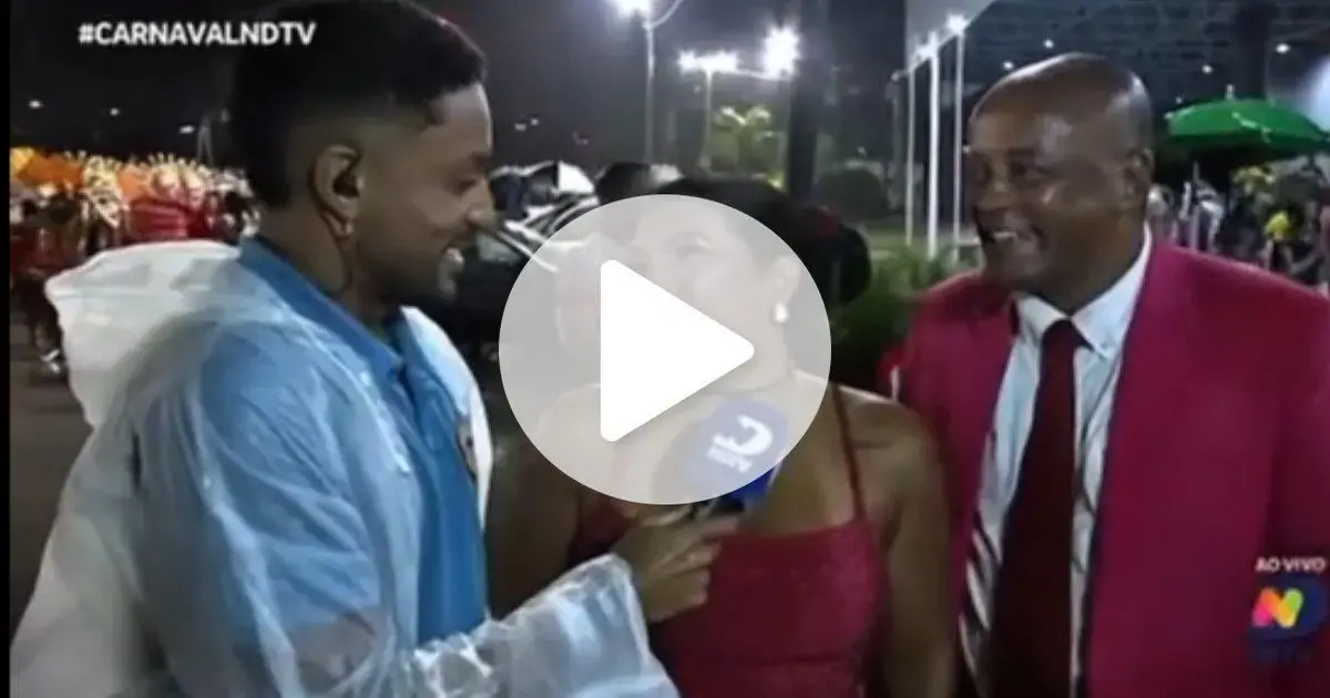 Repórter com capa de chuva entrevista casal sorridente durante o Carnaval de Florianópolis à noite.