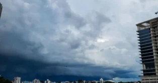 Céu nublado com nuvens escuras, prédios ao fundo, indicando risco de temporais e alagamentos.