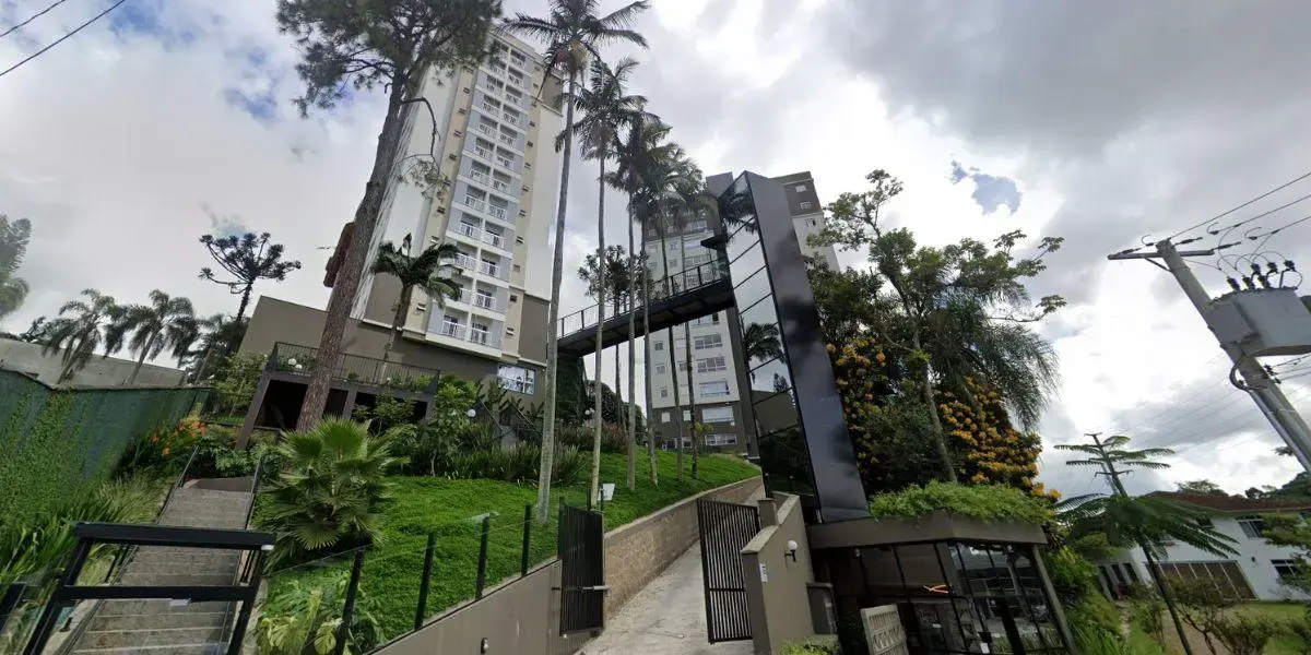 Edifício moderno com jardim, palmeiras e escadas, em dia nublado, no centro de uma cidade.