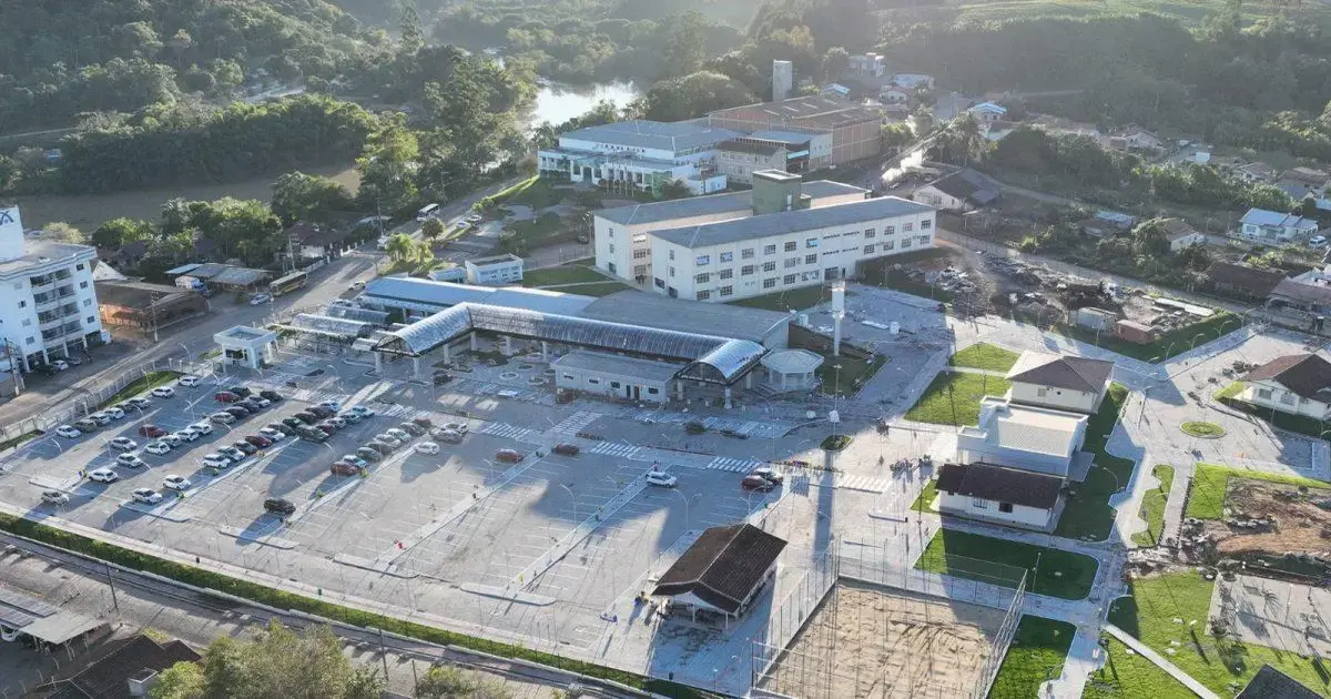 Vista aérea de campus universitário com prédios, estacionamento e áreas verdes ao redor.