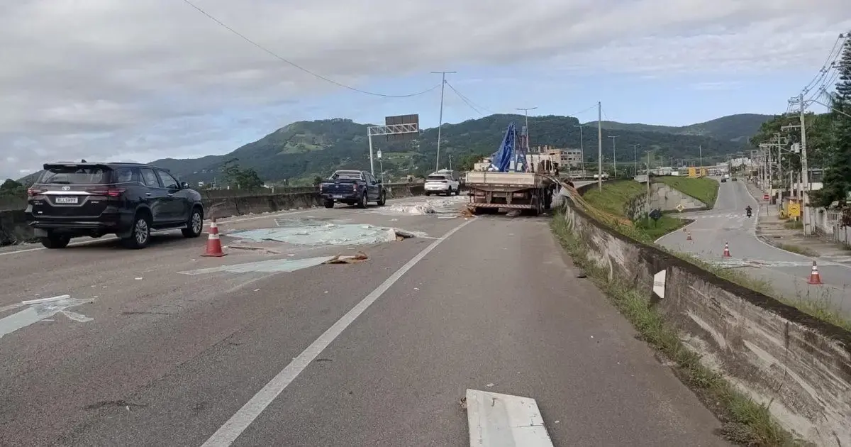 Bloqueio parcial na BR-101 em Biguaçu, com veículos parados e caminhão tombado na pista.
