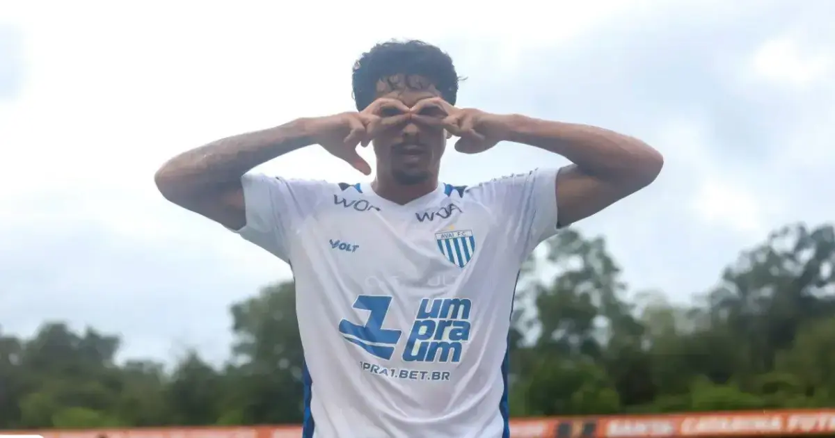 Atleta vestindo camisa branca do Avaí FC, fazendo gesto com as mãos em forma de óculos.