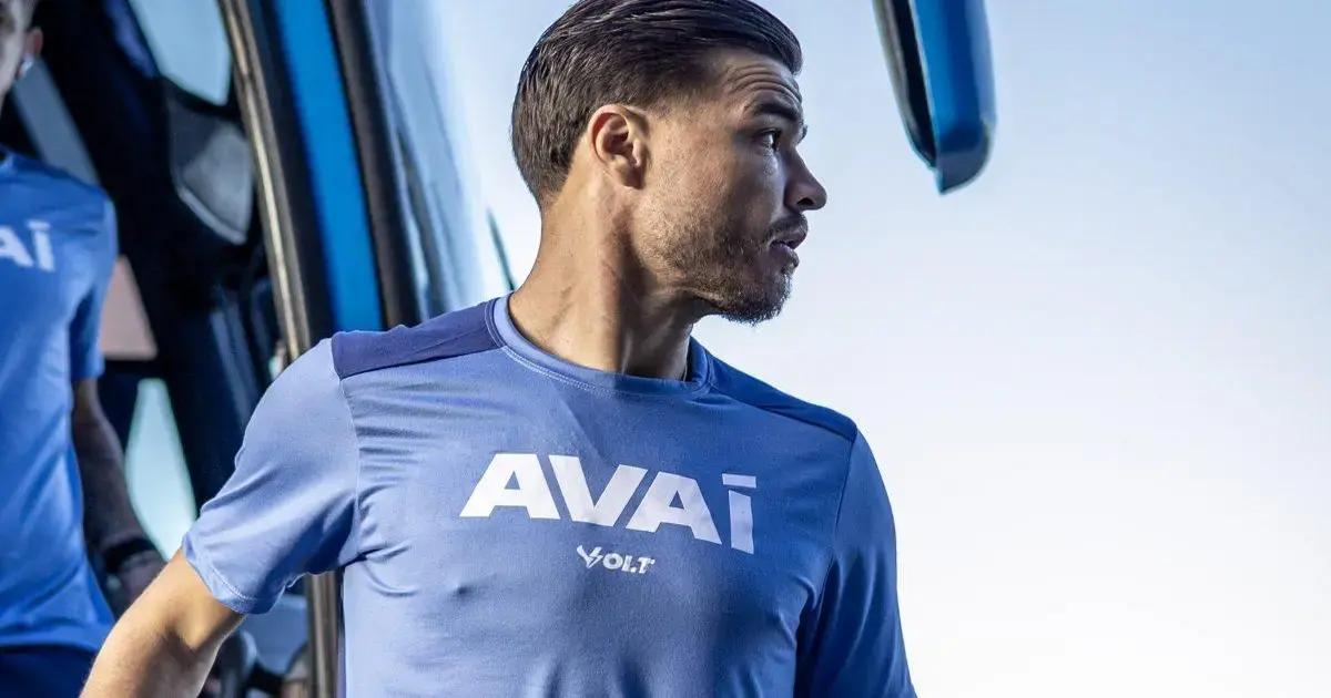 Atleta em uniforme azul do Avaí saindo de um ônibus, com a palavra 