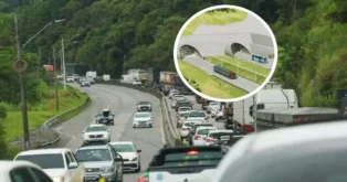 Tráfego intenso na BR-101 com caminhões e carros, e uma projeção de túnel ao fundo.