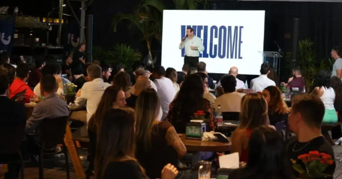 Público em evento com apresentação no telão contendo a palavra 