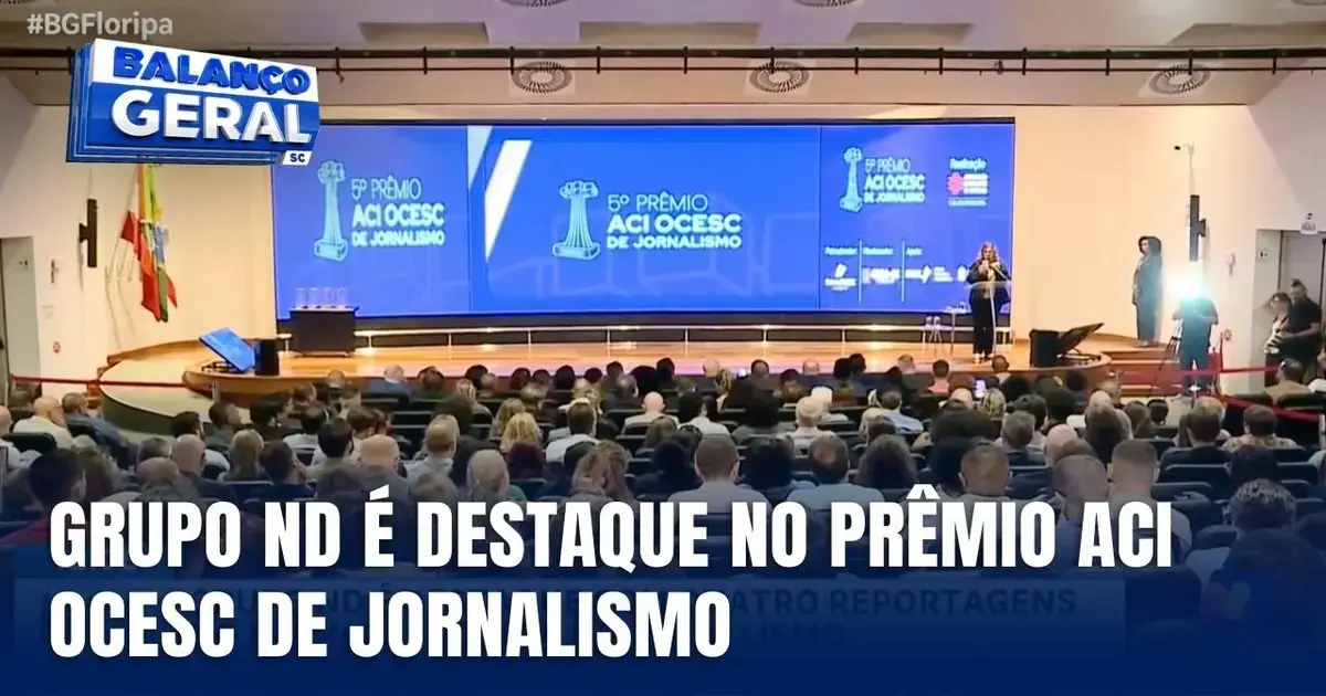 Plateia assistindo ao evento do 5º Prêmio ACI OCESC de Jornalismo, com telão exibindo informações sobre a premiação.