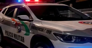 Veículo da Polícia Militar com sirenes ligadas, destacando a cor branca e detalhes em verde e vermelho.