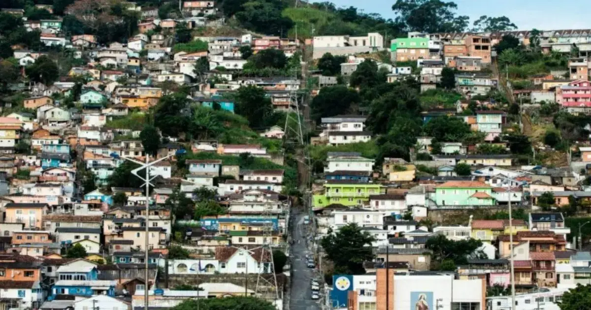 Vista de casas coloridas em um morro, com uma rua central e vegetação ao redor.