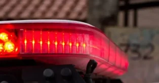 Luz de sirene vermelha com detalhes em laranja, visível na parte superior de um veículo.