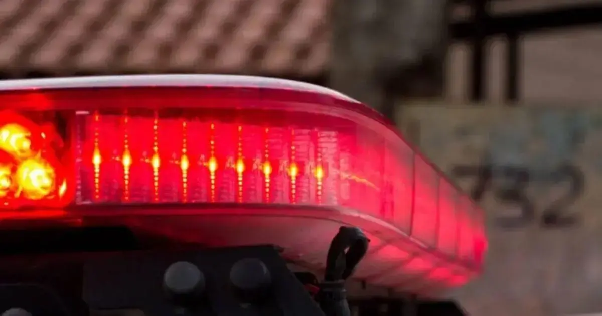 Luz de sirene vermelha com detalhes em laranja, visível na parte superior de um veículo.