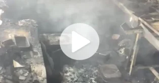 Ambiente de uma lanchonete após incêndio, com resíduos queimados e fumaça visível.