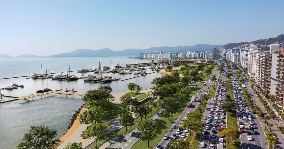 Vista aérea da Beira-Mar Norte em Florianópolis, com marina, barcos, calçadão e prédios ao fundo.
