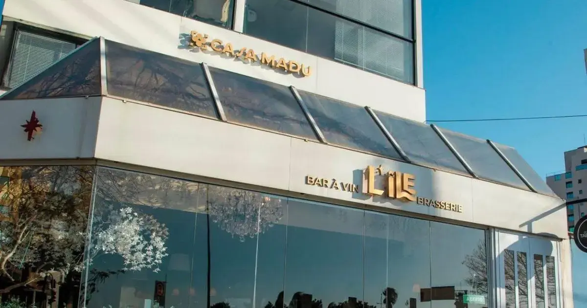 Fachada do restaurante L’Ile Brasserie com logo em destaque e iluminação complementando a entrada.