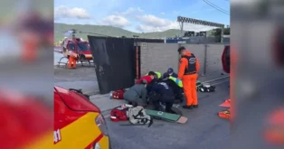 Grupo de socorristas prestando atendimento em local de acidente, com equipamentos de emergência ao redor.