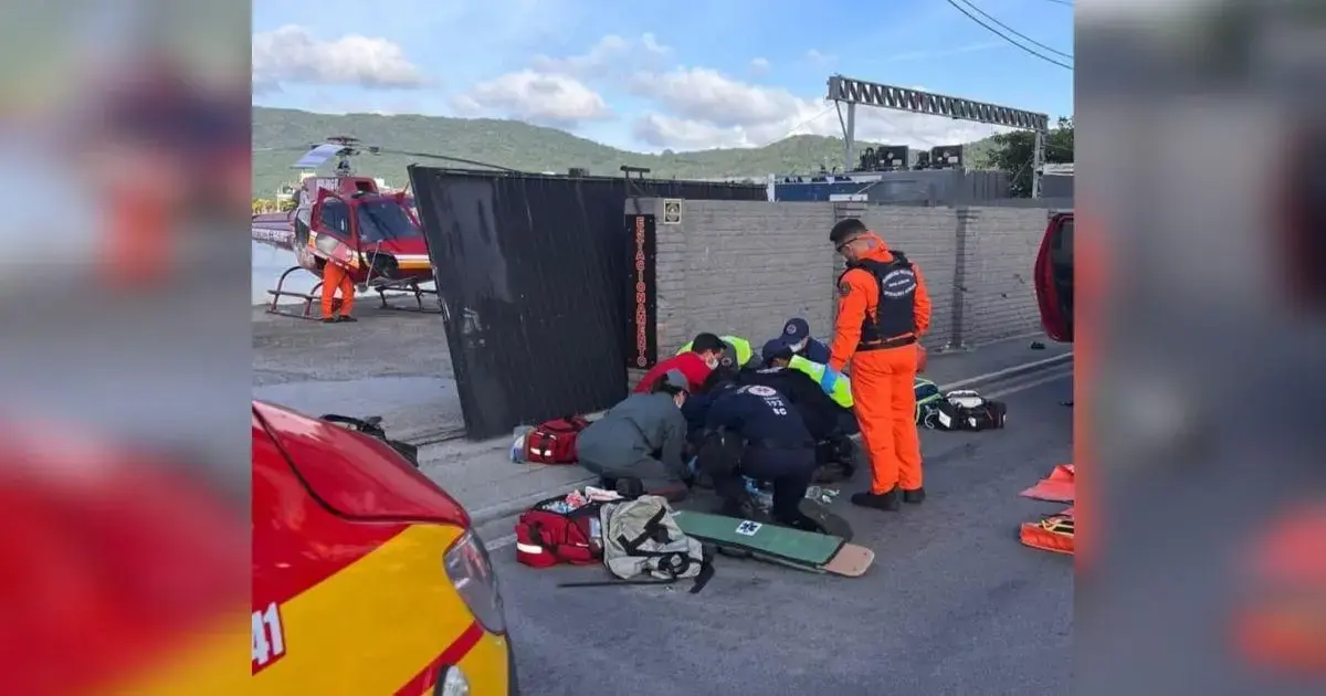 Grupo de socorristas prestando atendimento em local de acidente, com equipamentos de emergência ao redor.