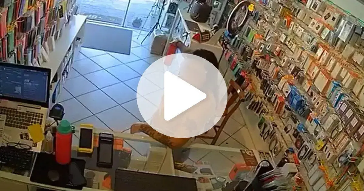 Interior de loja com produtos em exibição, atendente sentado em uma cadeira com um computador na mesa.