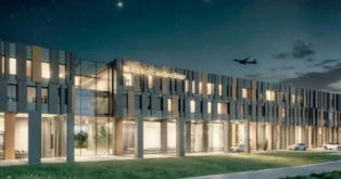 Fachada do hotel Hilton Garden Inn iluminada à noite, com carinhas em um fundo estrelado e um avião no céu.