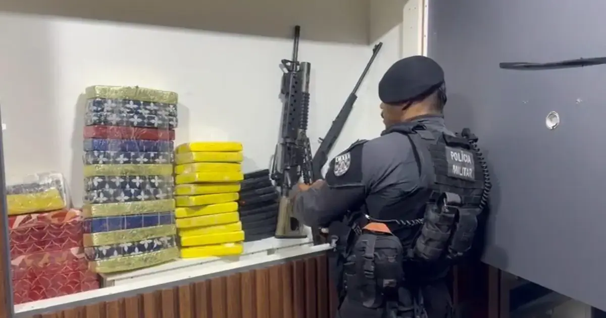 Militar inspecionando armamento ao lado de pacotes de drogas em um ambiente controlado.