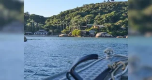 Vista da pousada Ilha do Papagaio com vegetação exuberante e água tranquila ao fundo.