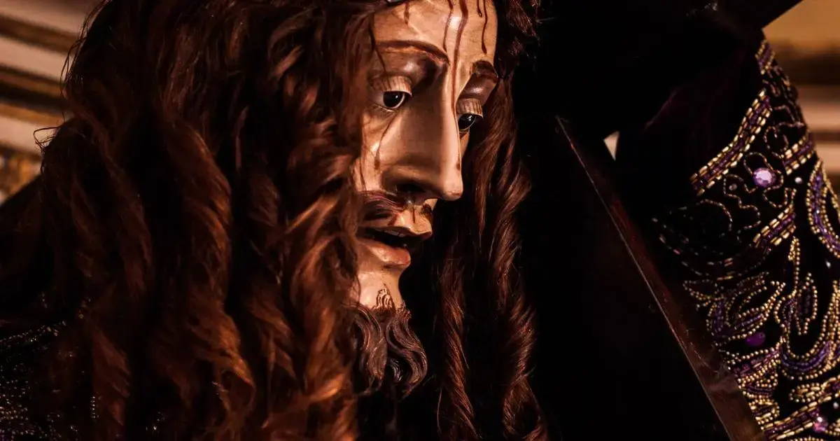 Detalhe de uma escultura com cabelos longos e ondulados, expressão séria e vestes ornamentadas.