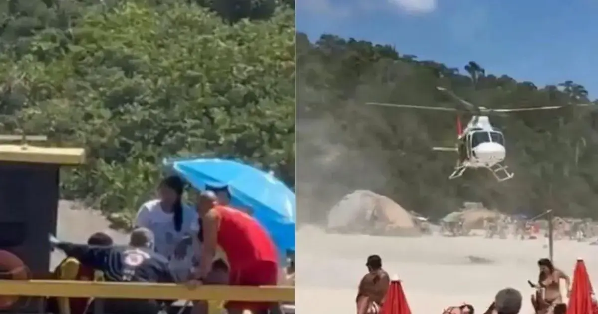 Helicóptero sobrevoa praia enquanto pessoas se reúnem em torno de uma embarcação próxima a uma vegetação.